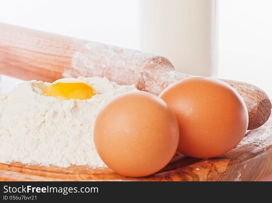 Vintage rolling pin with flour and eggs. Country still life images with soft lighting and small degrees of freedom (selective focus on the yolk)