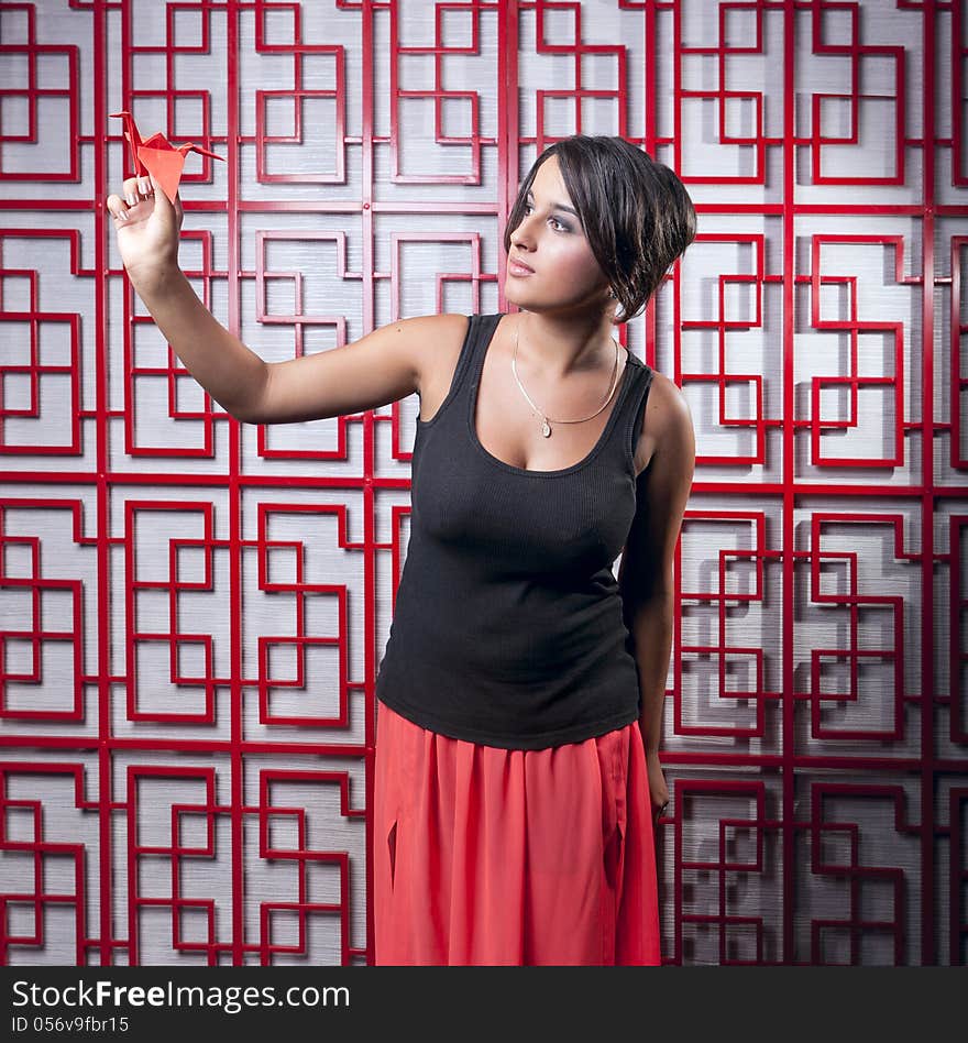 Beautiful girl holding paper crane over Red lattice