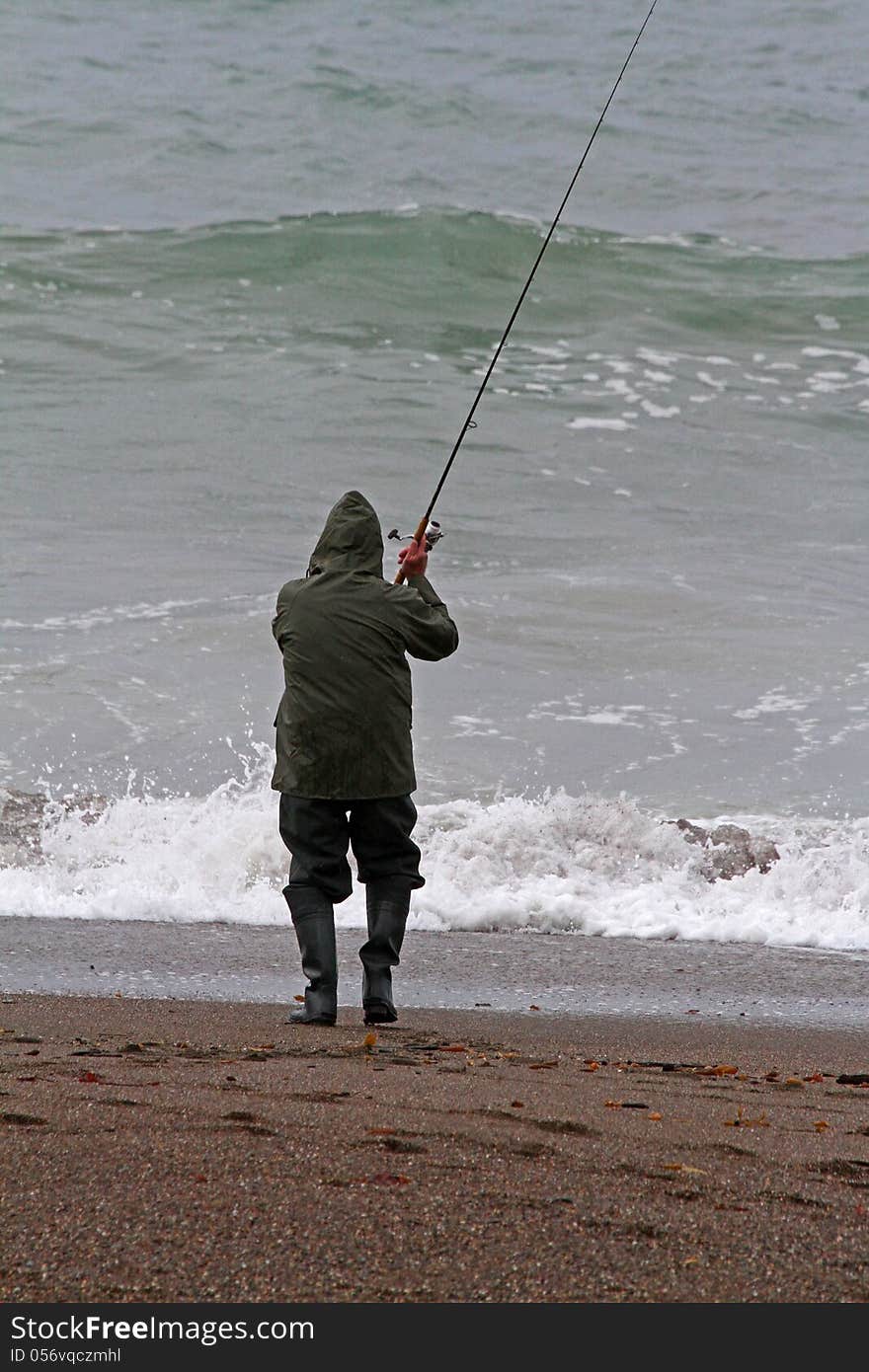 Lone Man Surf Fishing In Ocean During Storm. Lone Man Surf Fishing In Ocean During Storm