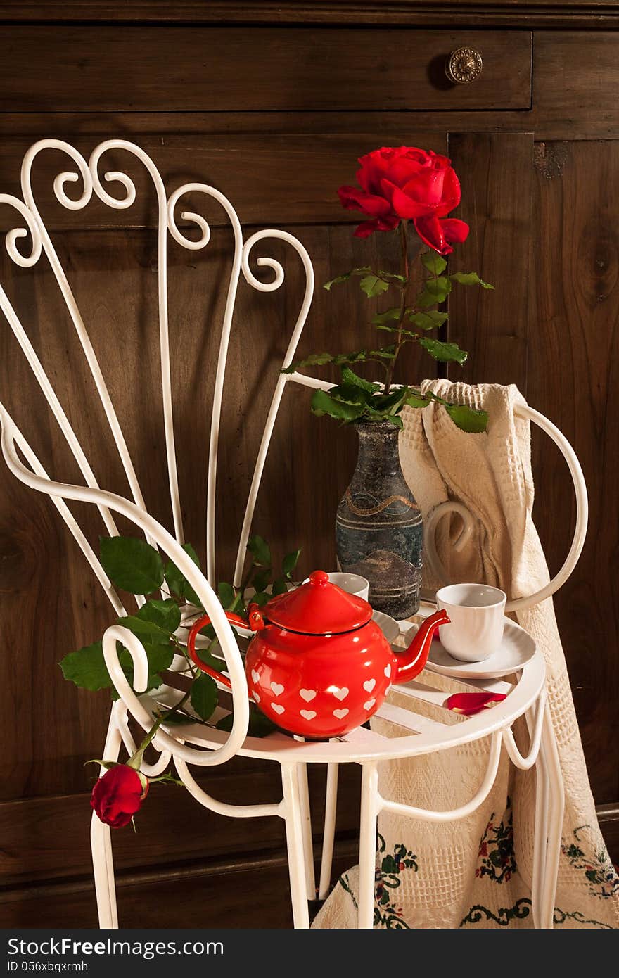 A still life with antique chair, flowers and tea