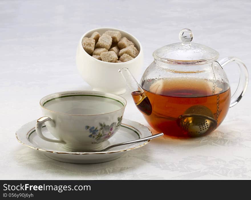 Teapot with tea, cup on a saucer and sugar bowl with brown and w