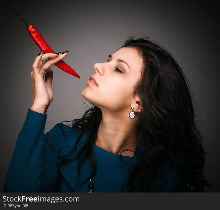 Woman holding red hot chili pepper in mouth