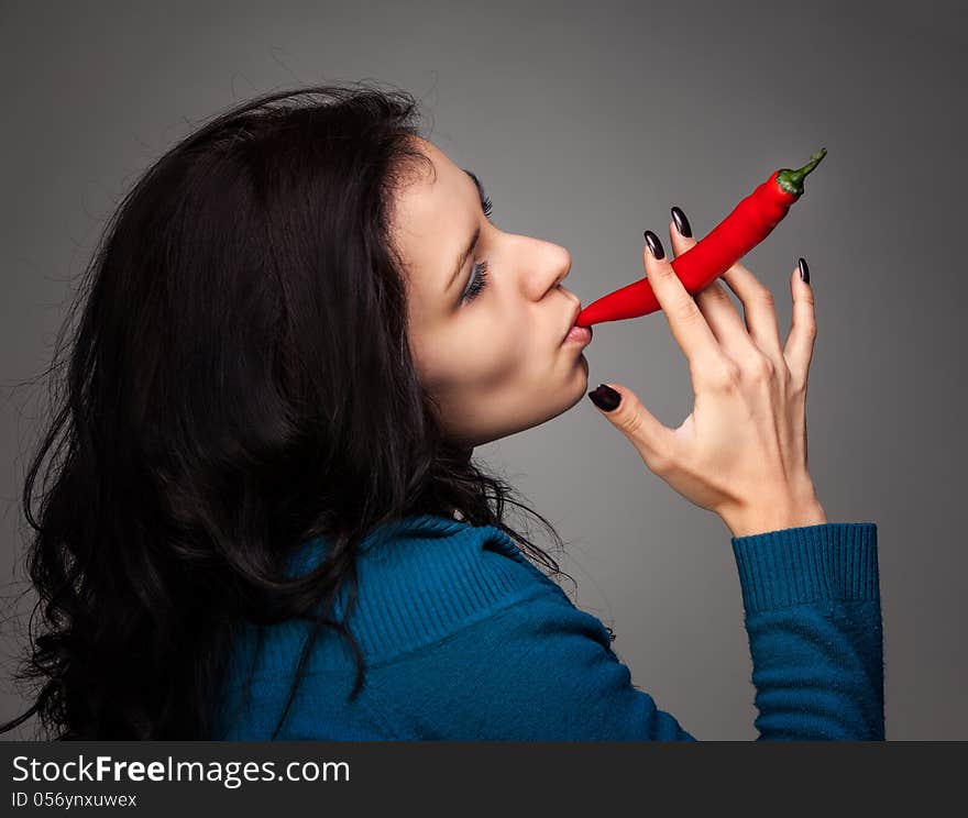 Young lady holding red hot chili pepper in mouth. Young lady holding red hot chili pepper in mouth