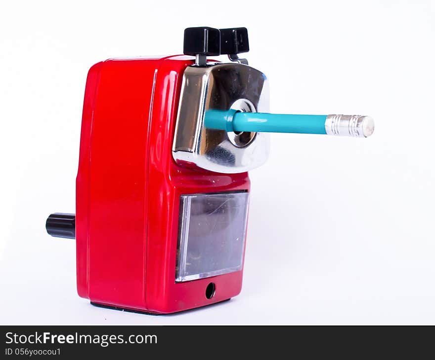 Red pencil sharpener with green pencil on white background