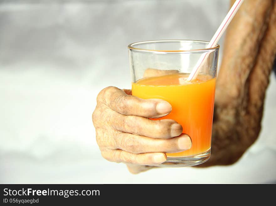 An old aged hand holding a glass of orange juice. An old aged hand holding a glass of orange juice