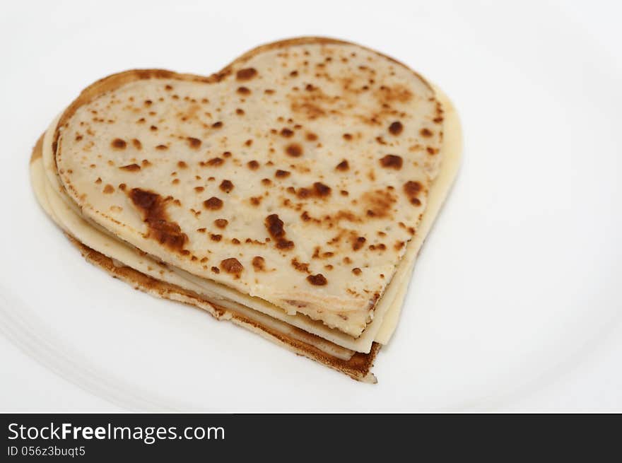 Heart-shaped pancakes lying on white plate isolated. Heart-shaped pancakes lying on white plate isolated