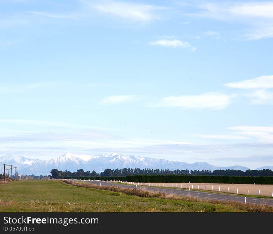 Long road stretching out into the distance with snow mountain background in New Zealand