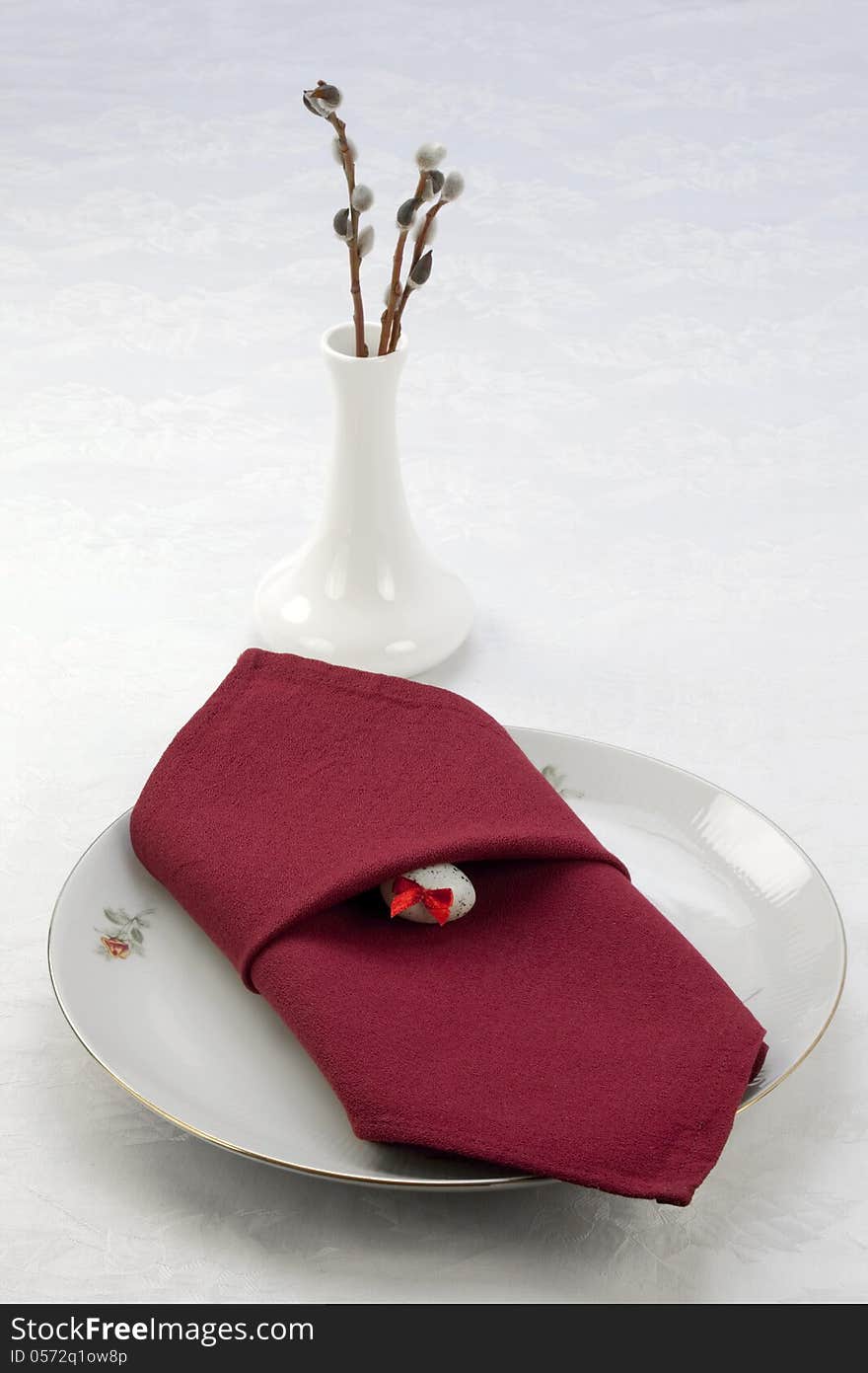 On the dining table - a dish decorated with red napkin and easter egg, and a vase with branches of willow. On the dining table - a dish decorated with red napkin and easter egg, and a vase with branches of willow.