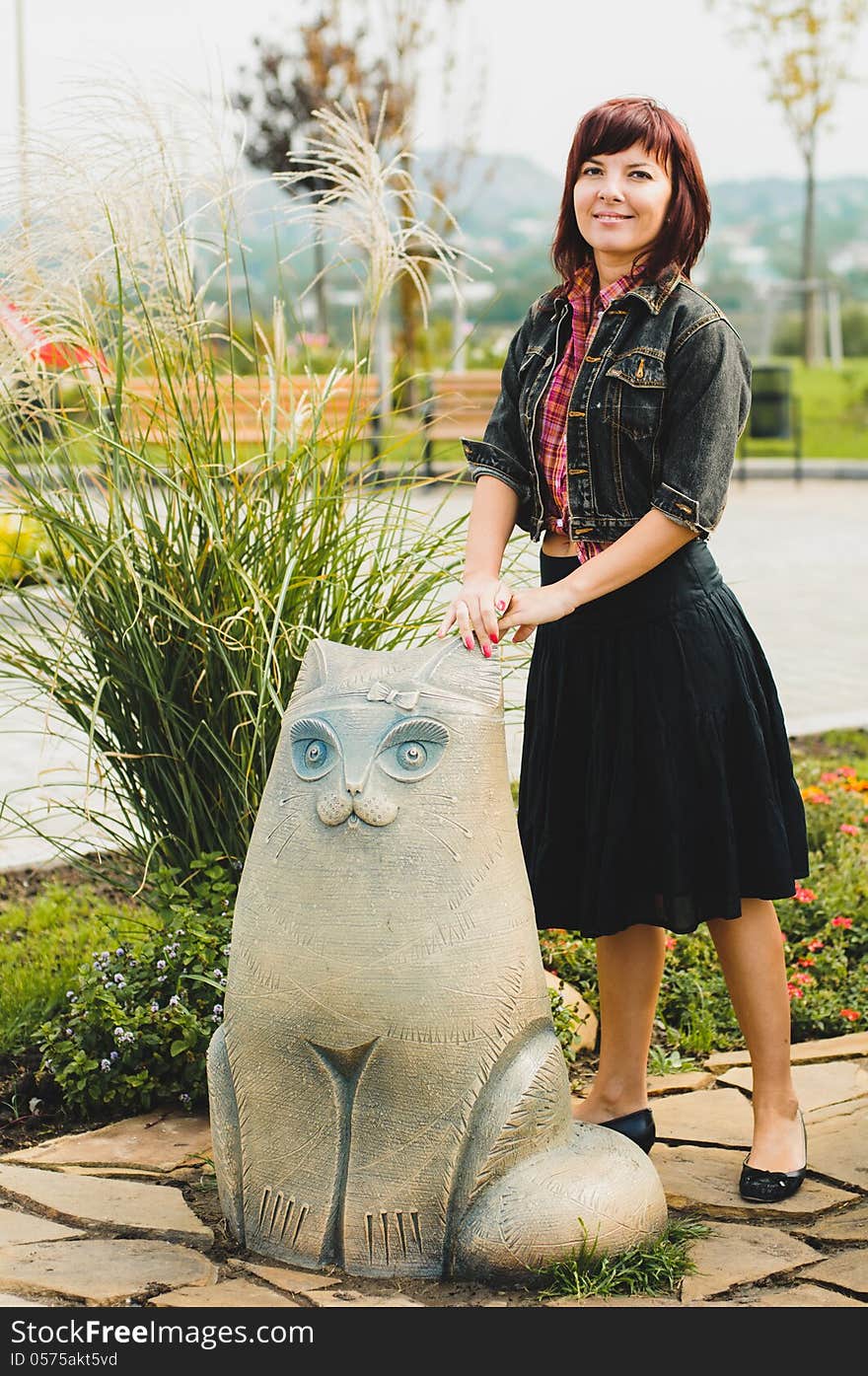 Young woman standing near funny cat statue