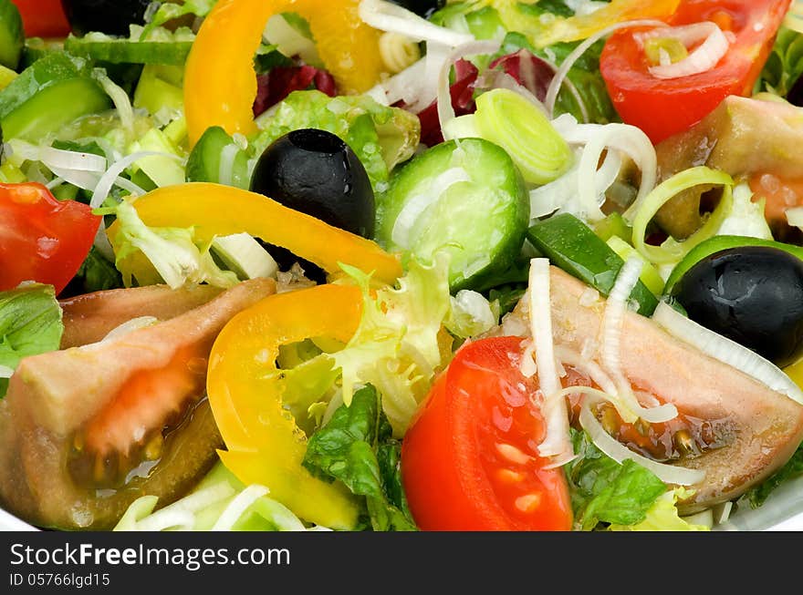 Background of Vegetable Salad with Tomatoes, Yellow Bell Pepper, Leek, Black Olive, Cucumber, Lettuce and Olive Oil closeup