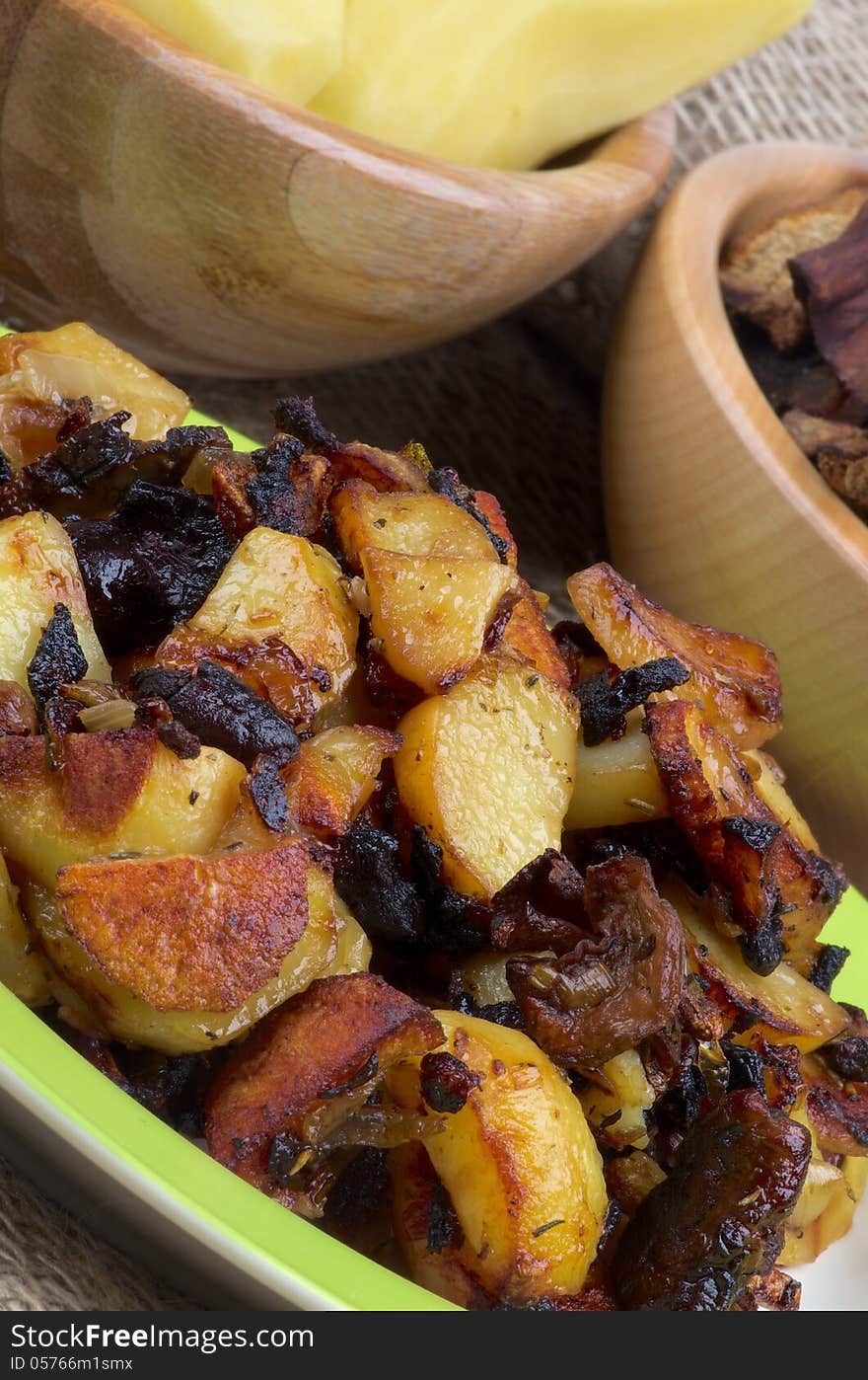 Roasted Potato with Mushrooms and Onion on Two Wood Bowls with Raw Potato, Onion and Slices of Mushrooms background