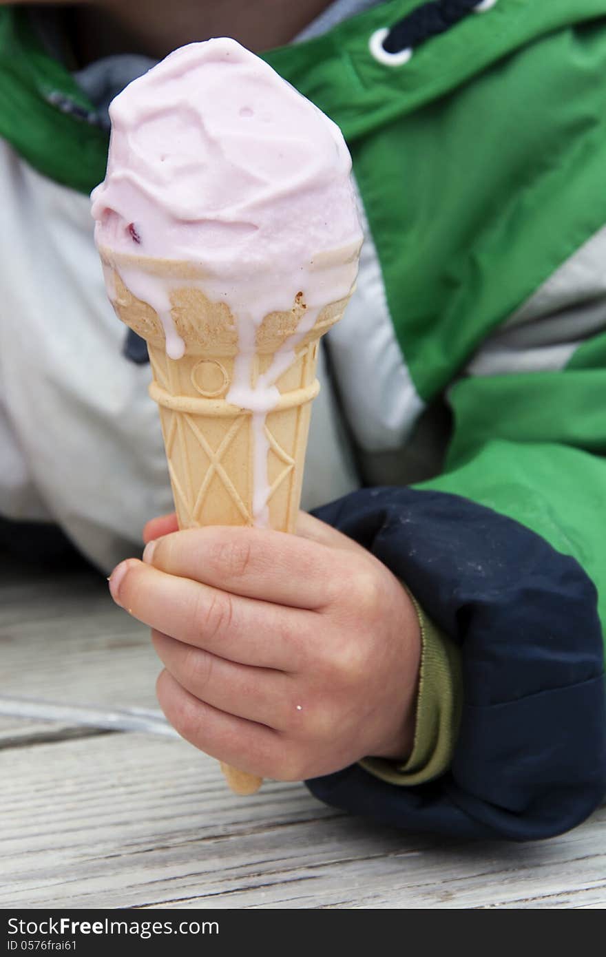 Ice cream in a cone in a hand of a child.