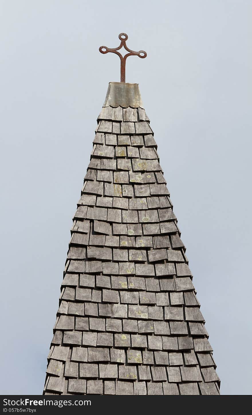 An old cross on top of an old wooden tile roof