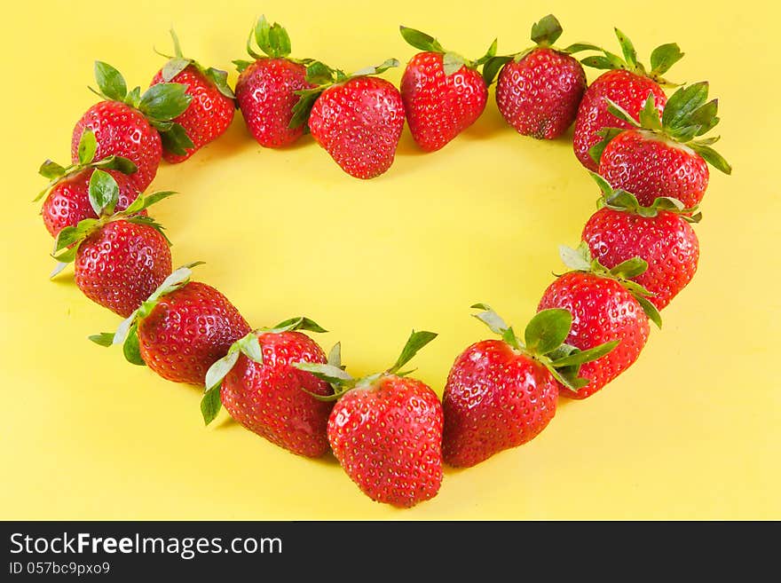 Strawberries heart on yellow background