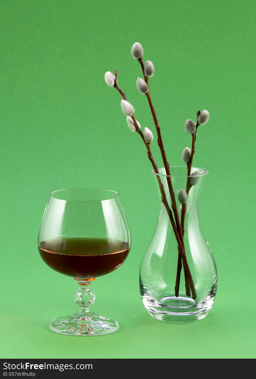 A glass of red wine and a transparent vase with willow sprigs. A glass of red wine and a transparent vase with willow sprigs