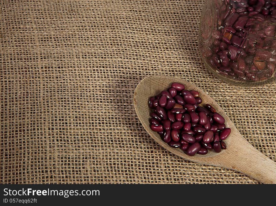 Red beans that are out a mason jar on a rough textured burlap backgroud-background. Red beans that are out a mason jar on a rough textured burlap backgroud-background.