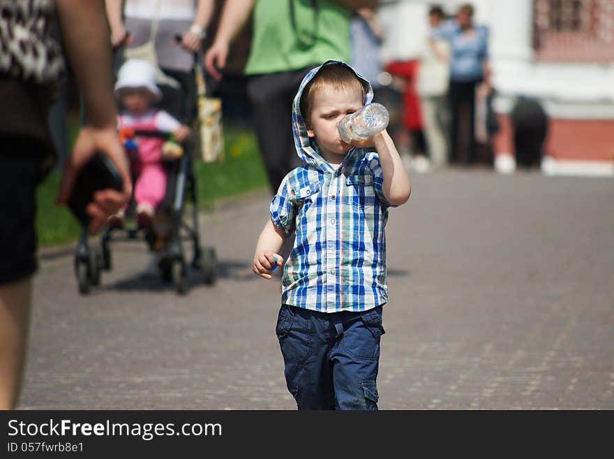 Little boy drinking from plastic bottle on a hot day