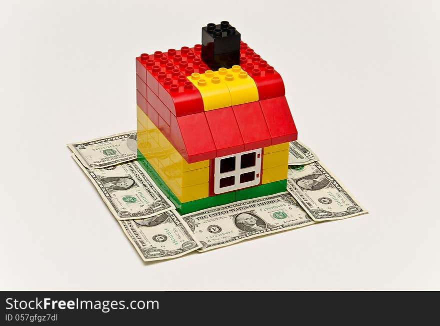 LEGO house and money. Dollars in front of the house.