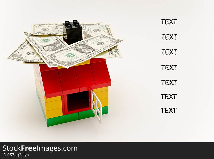 LEGO house and money. Dollars on the roof. Text next to the house.