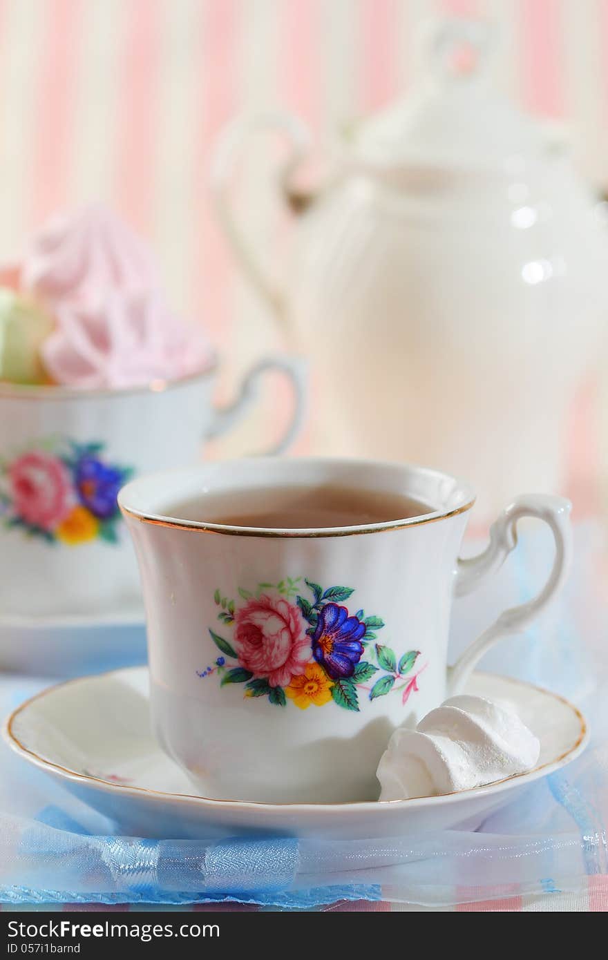 Black tea in elegant cup with colorful meringue cookies. Black tea in elegant cup with colorful meringue cookies