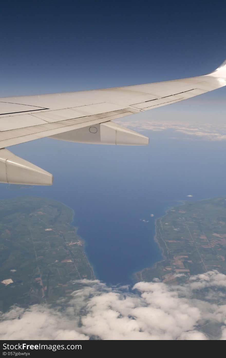 Commercial airplane flying with deep blue sky above and land and clouds below. Commercial airplane flying with deep blue sky above and land and clouds below