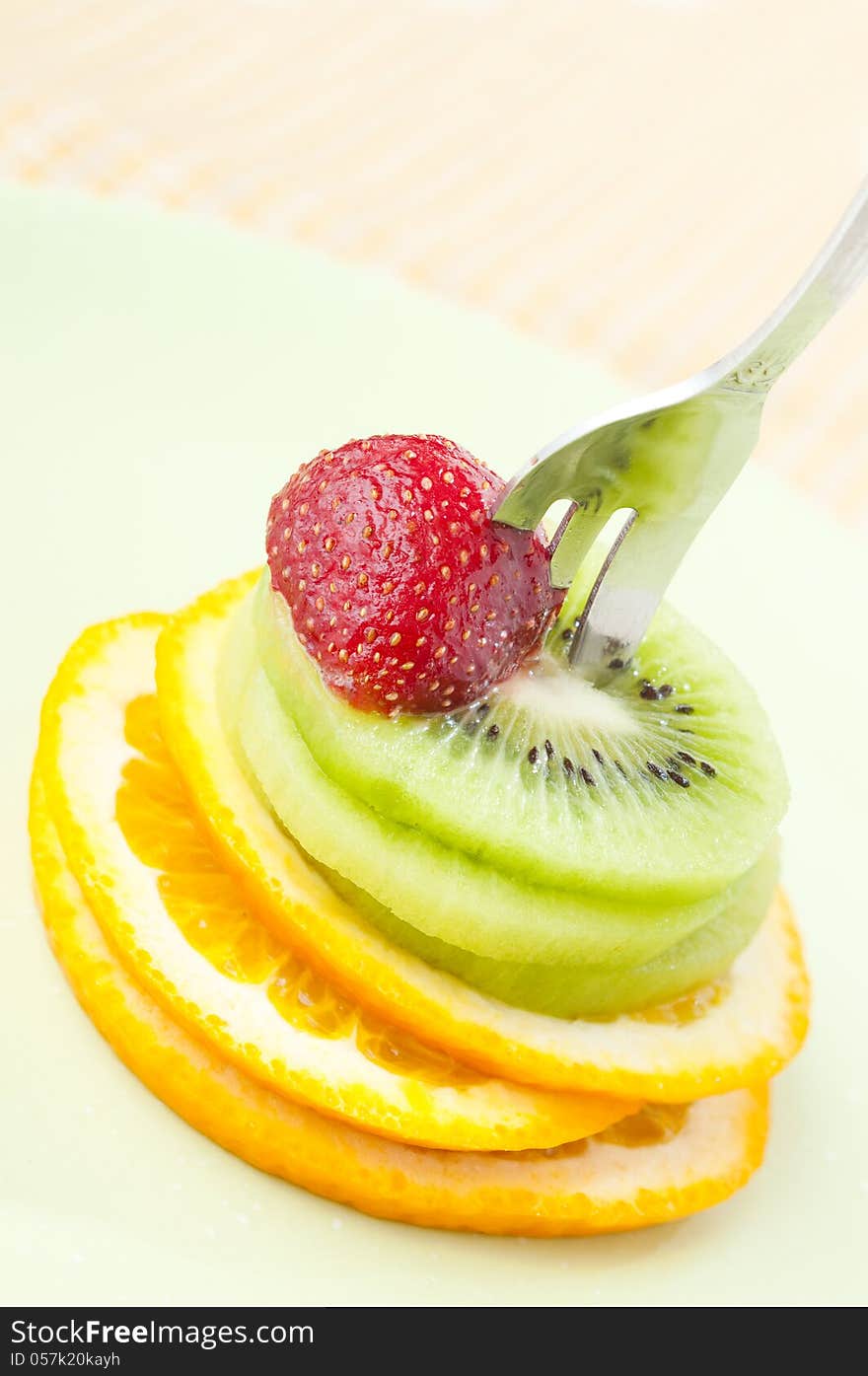 Sliced orange, kiwi fruits and strawberry on a fork. Sliced orange, kiwi fruits and strawberry on a fork