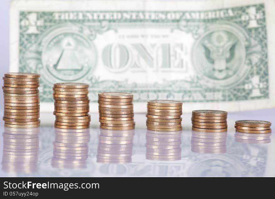 Columns of gold coin. In front of one dollar bill