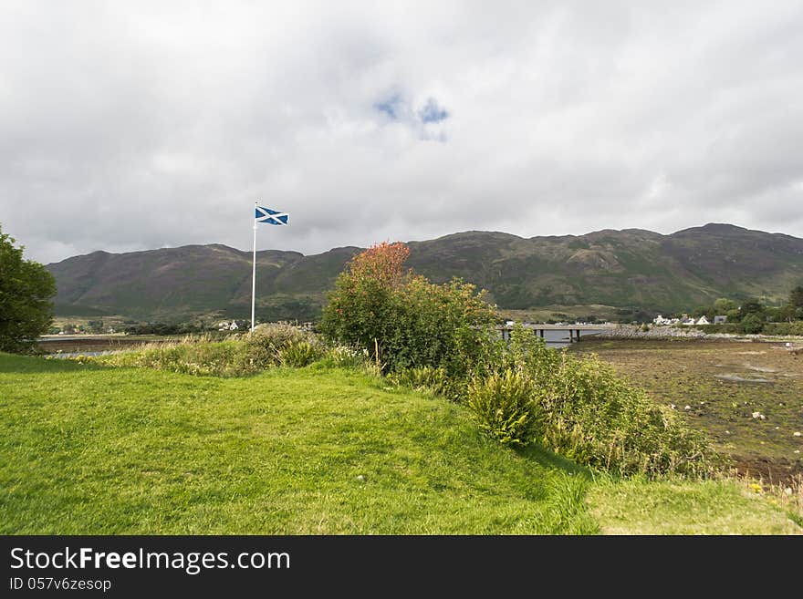 The Saltire flag above near Eilean Donan Castle, Dornie Village, Skye Island Scotland. The Saltire flag above near Eilean Donan Castle, Dornie Village, Skye Island Scotland