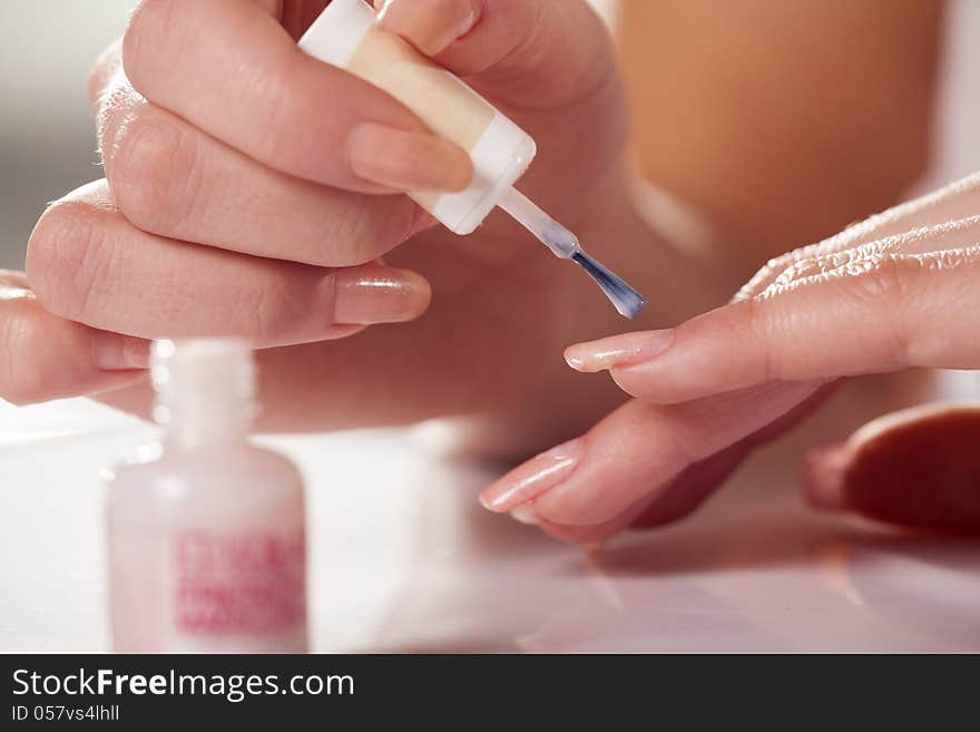 Close up of woman applying neutral nail polish