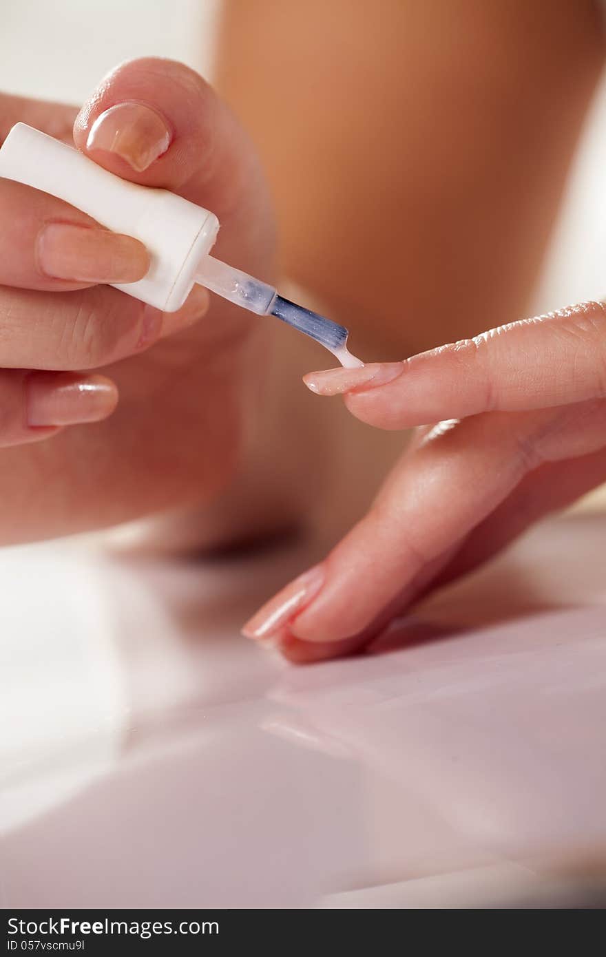 Close up of woman applying neutral nail polish