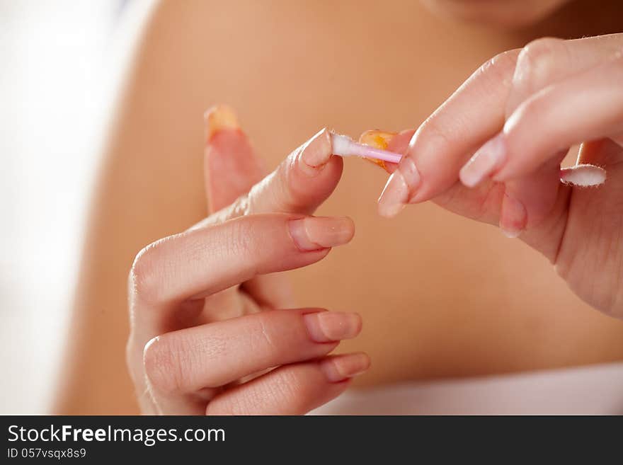 Girl cleans her nails with a cotton swab with focus on foreground. Girl cleans her nails with a cotton swab with focus on foreground