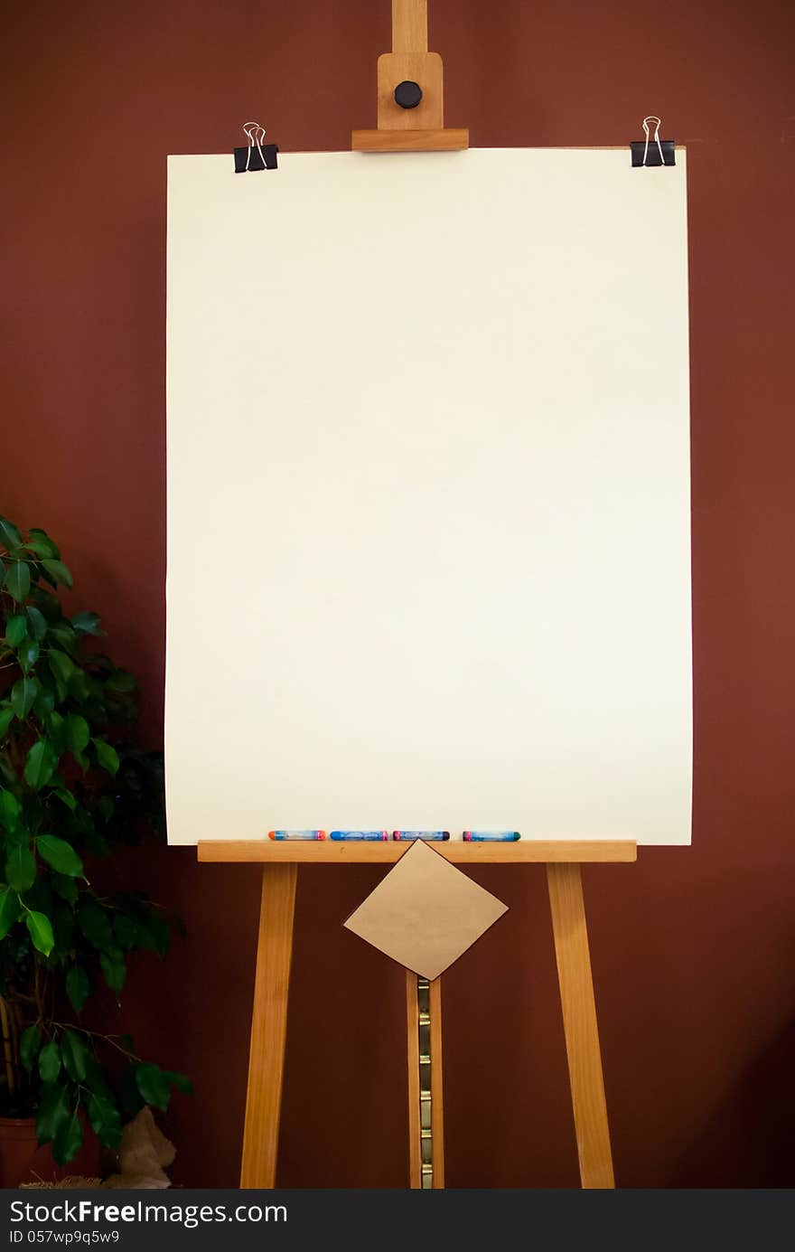 Wooden Art Easel with white paper on Brown Background. Wooden Art Easel with white paper on Brown Background