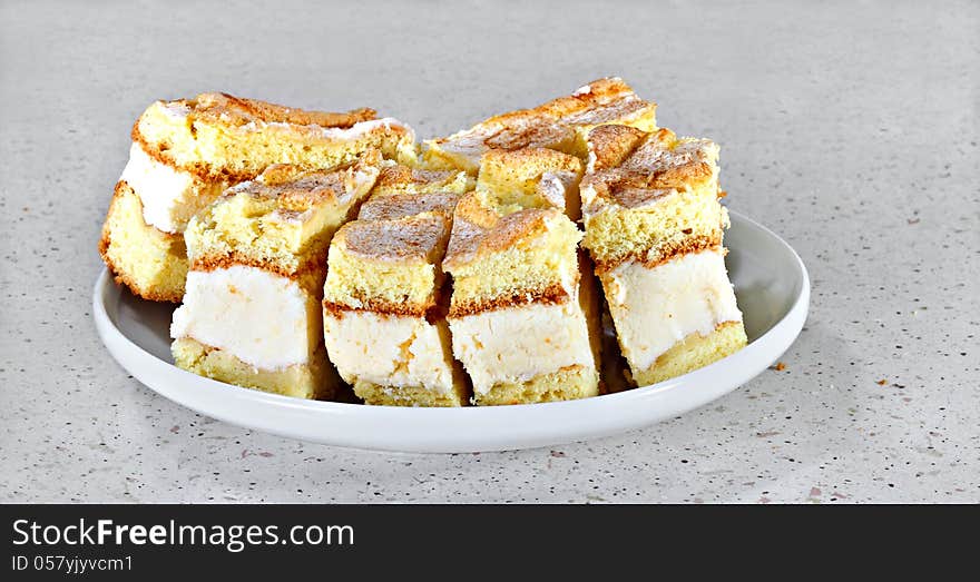 Sponge cakes with white cream and cinnamon on gray table. Sponge cakes with white cream and cinnamon on gray table