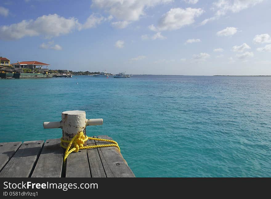 A steel bollard and nylon rope positioned on the end of a wooden dock represent secure mooring. A steel bollard and nylon rope positioned on the end of a wooden dock represent secure mooring.