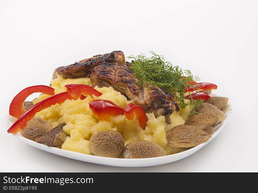 Plate with grilled fresh meat and mash potato, mashrooms and vegetables, against bright background