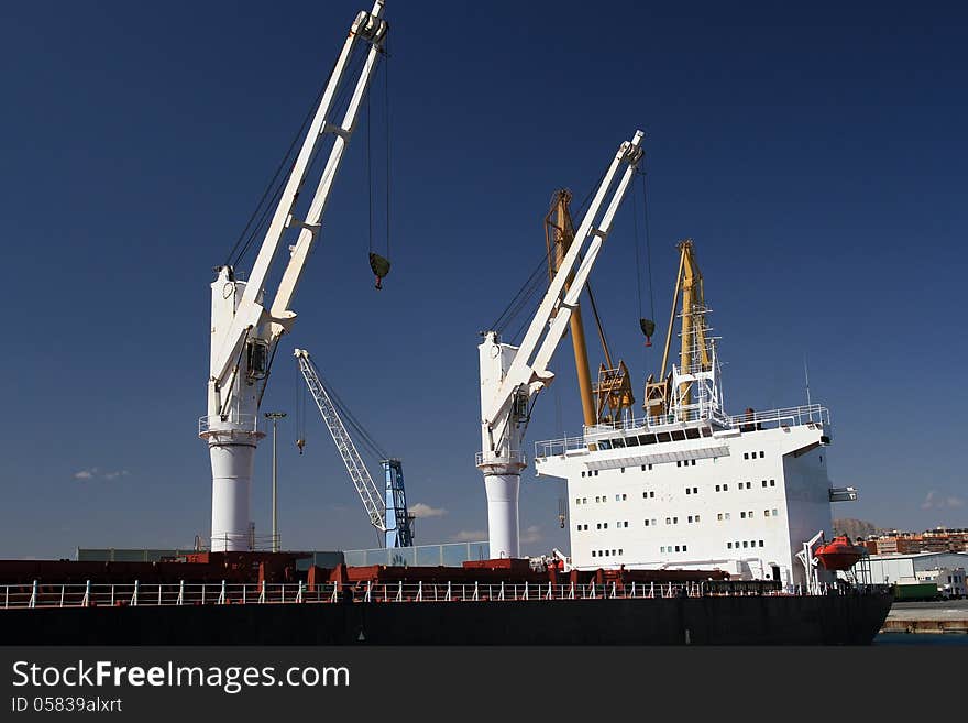 General cargo ship with cranes docked in the port of Alicante; Spain.