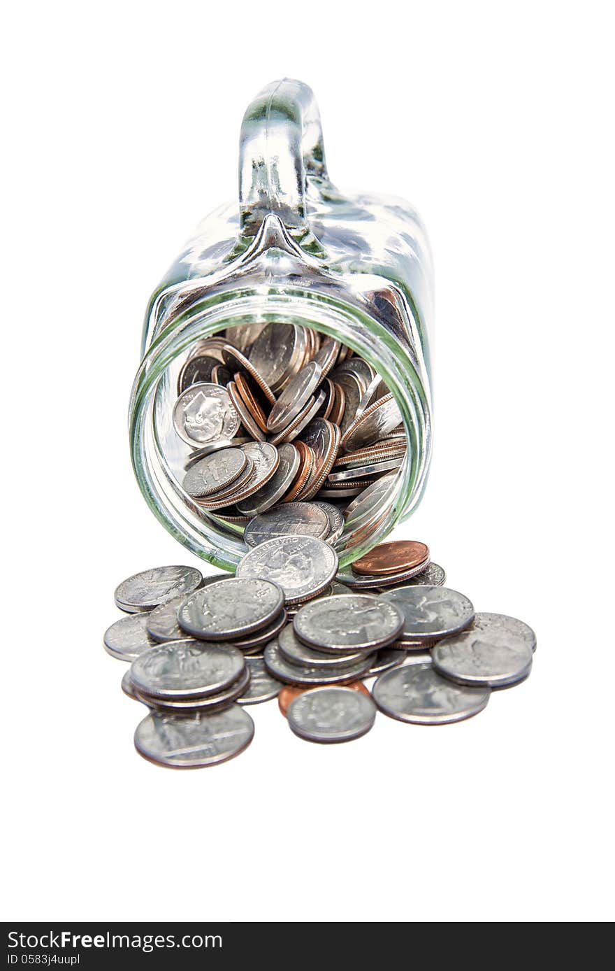 Vertical shot of many coins spilling out of a glass jar and isolated on a white background. Vertical shot of many coins spilling out of a glass jar and isolated on a white background.