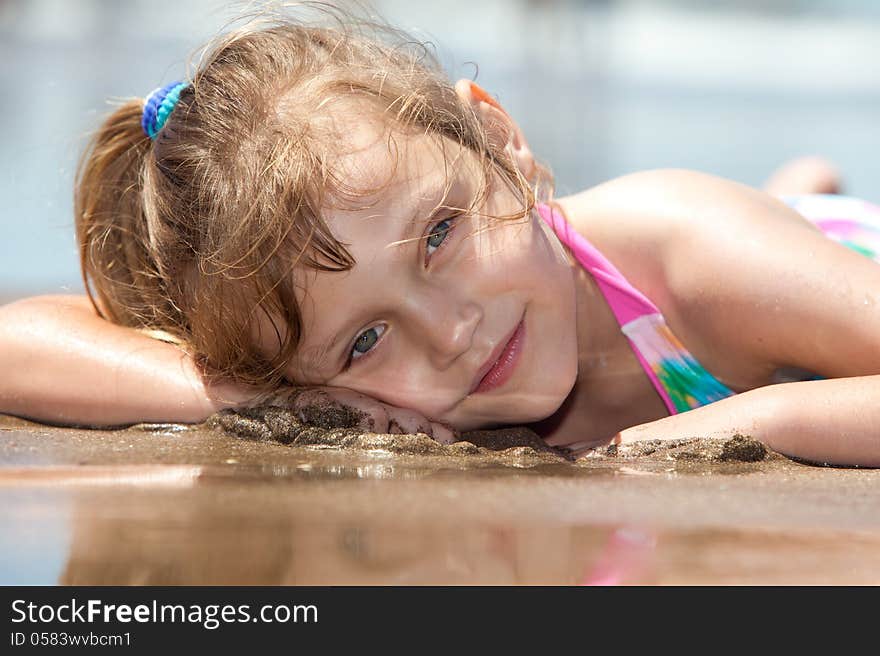 Portrait of a little girl lying down on the beach. Portrait of a little girl lying down on the beach