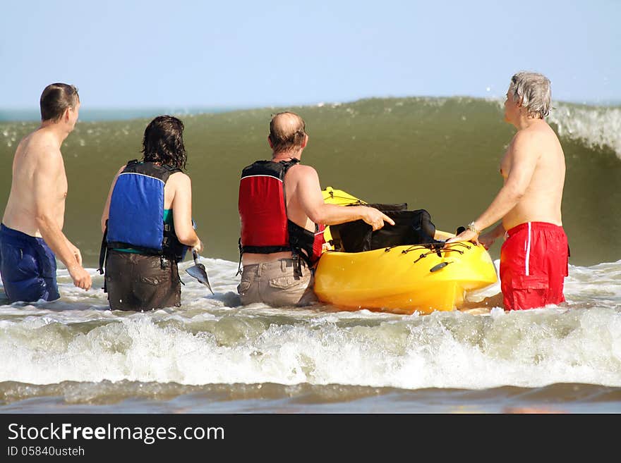 A group of middle aged friends analyzing a large wave that needs to be crossed with the kayak. A group of middle aged friends analyzing a large wave that needs to be crossed with the kayak