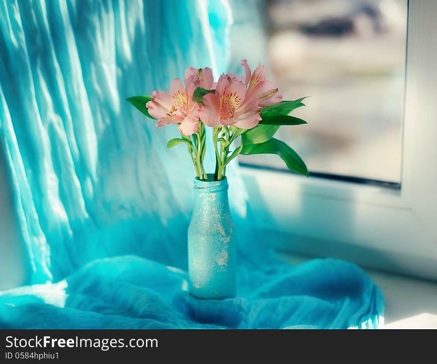 On a blue background and a blue vase delicate ornamental flowers. On a blue background and a blue vase delicate ornamental flowers