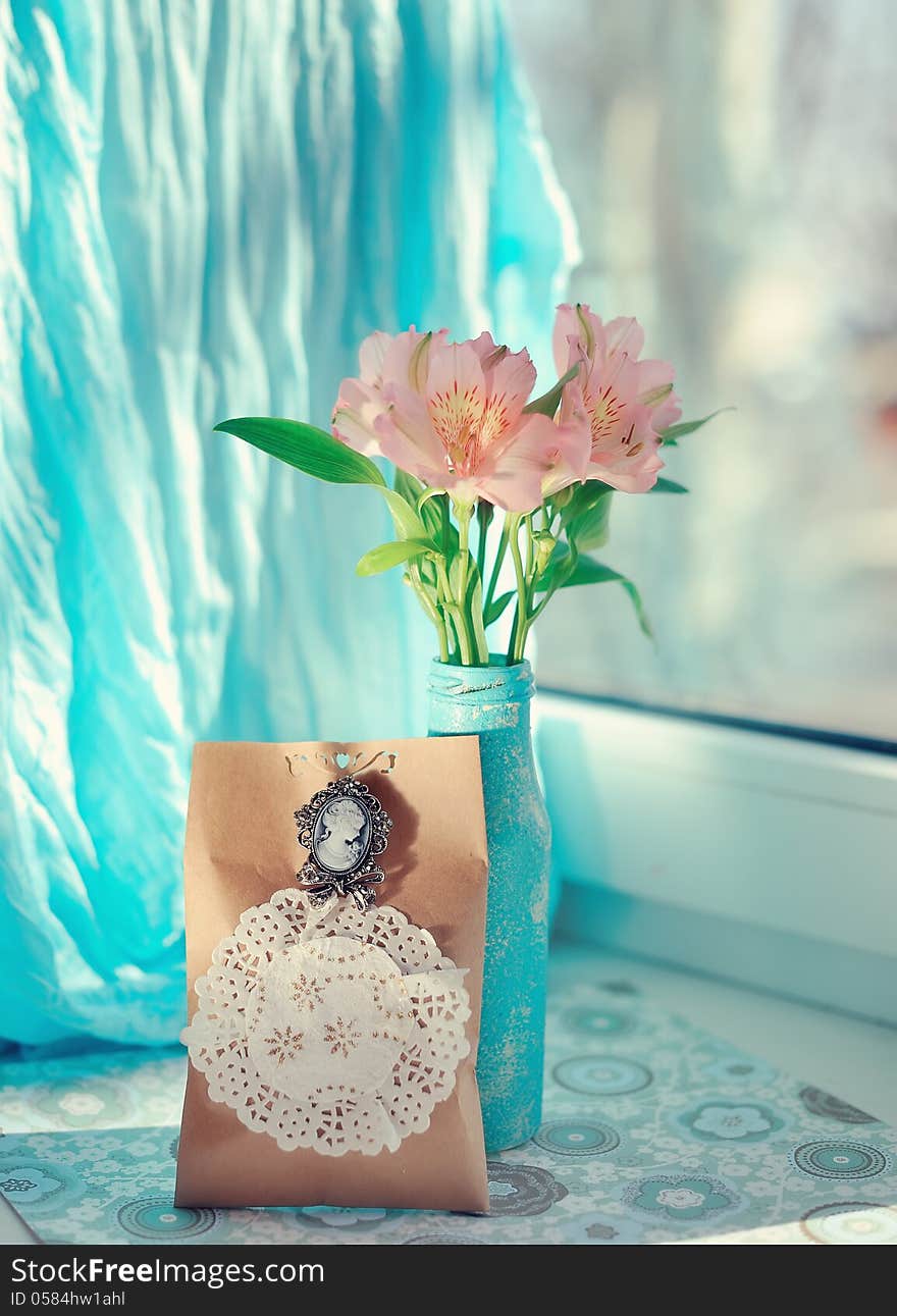 On a blue background and a blue vase delicate ornamental flowers and greeting card. On a blue background and a blue vase delicate ornamental flowers and greeting card