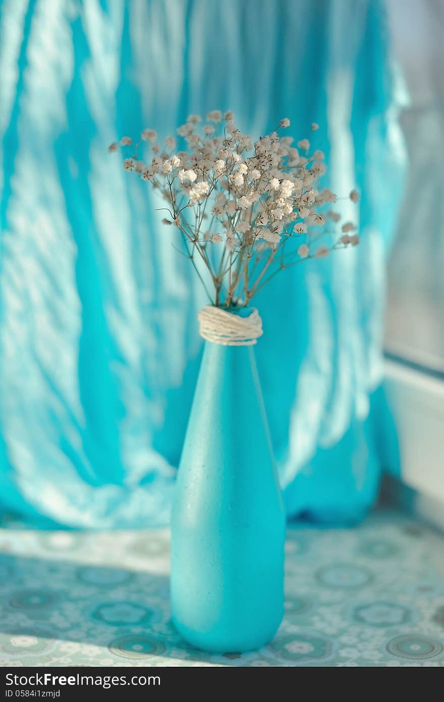 On a blue background and a blue vase delicate white flowers. On a blue background and a blue vase delicate white flowers