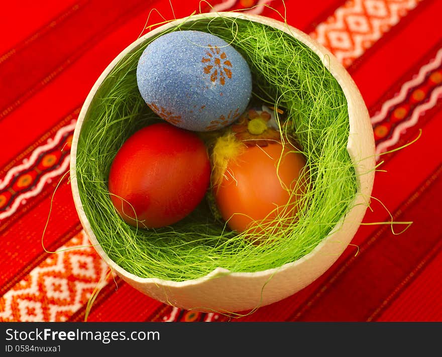 Colored Easter eggs in one big ostrich egg with grass.