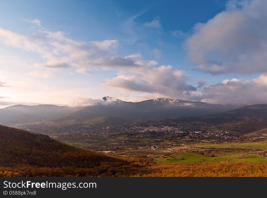 View of a village, green fields and meadows from the top of a mountain on a sunny autumn day