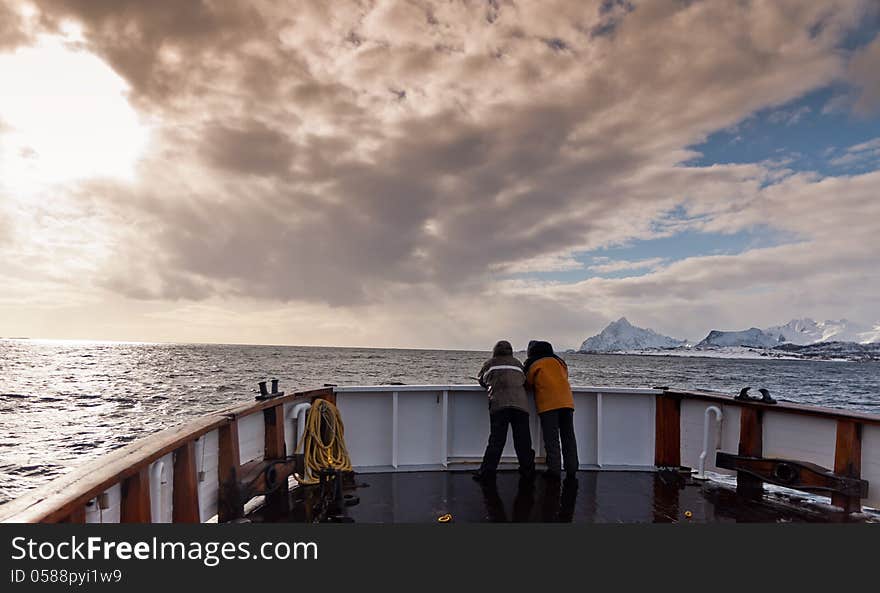 Two men in the prow of the ship sailing in the Norwegian fiords