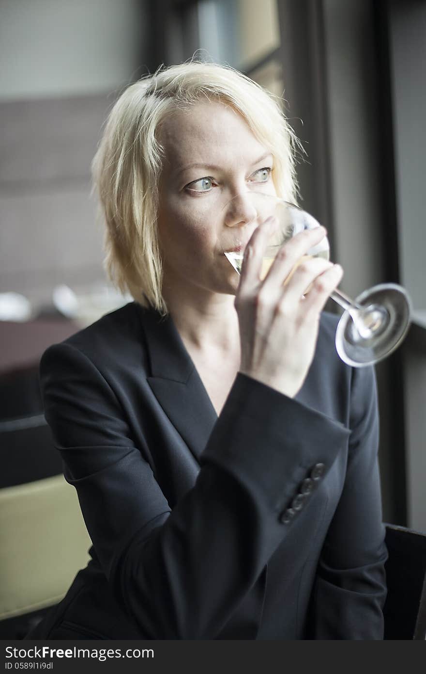 Blonde Woman with Beautiful Blue Eyes Drinking Glass of White Wi