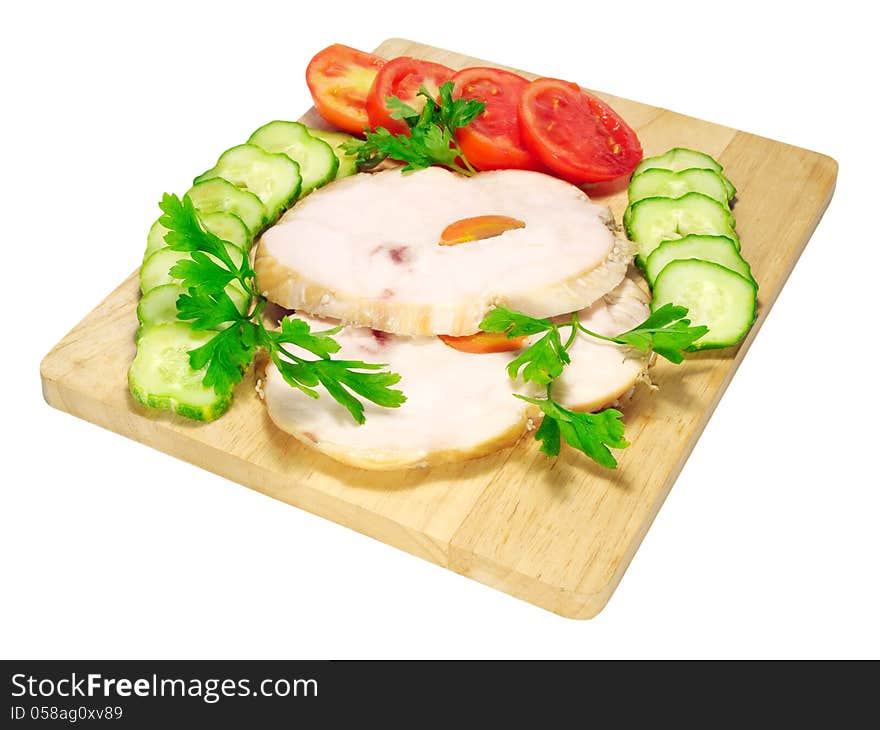 Two pieces of ham with tomatoes and cucumbers on a chopping board isolated on white background. Two pieces of ham with tomatoes and cucumbers on a chopping board isolated on white background