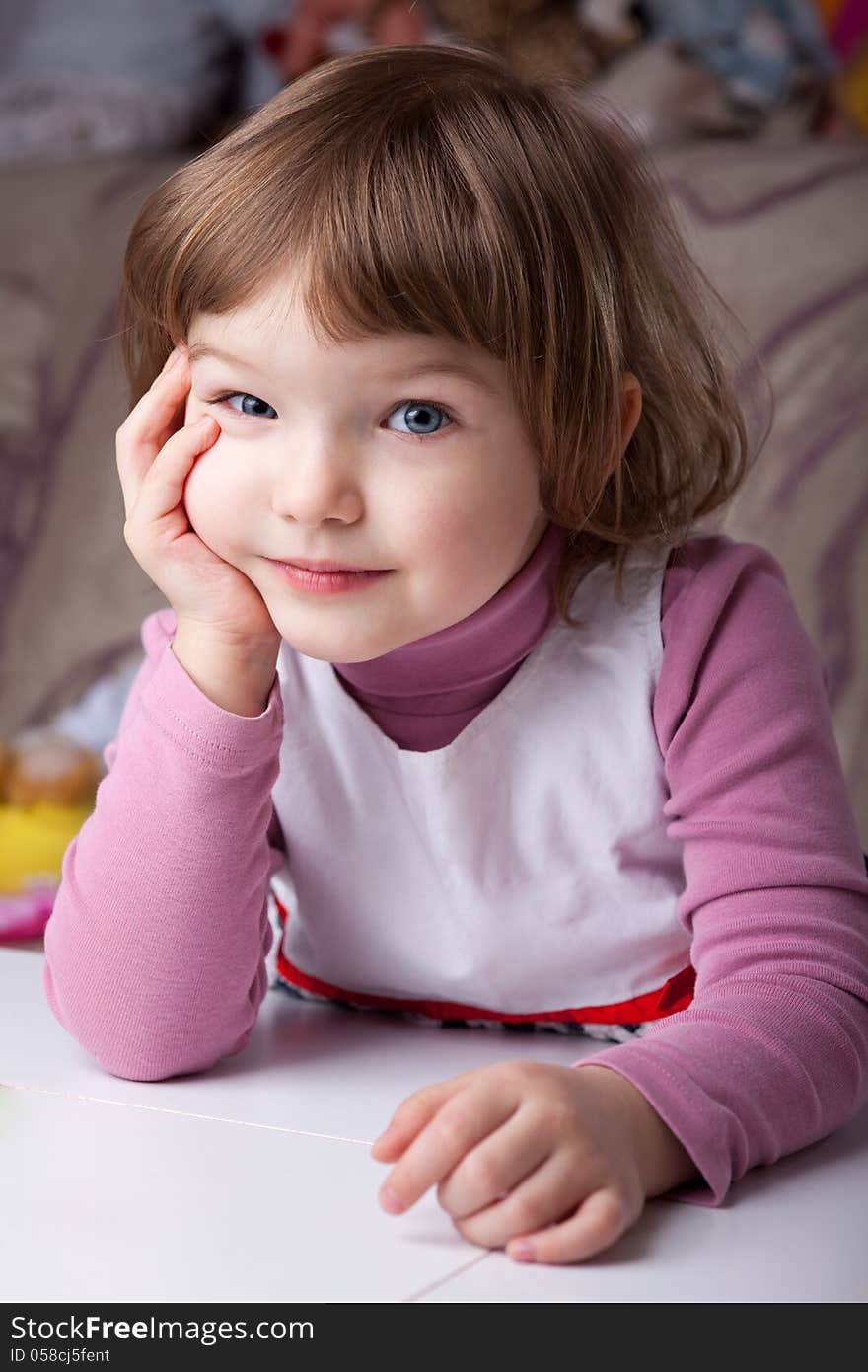 Girl sitting at the table with head resting on arm and looking curious