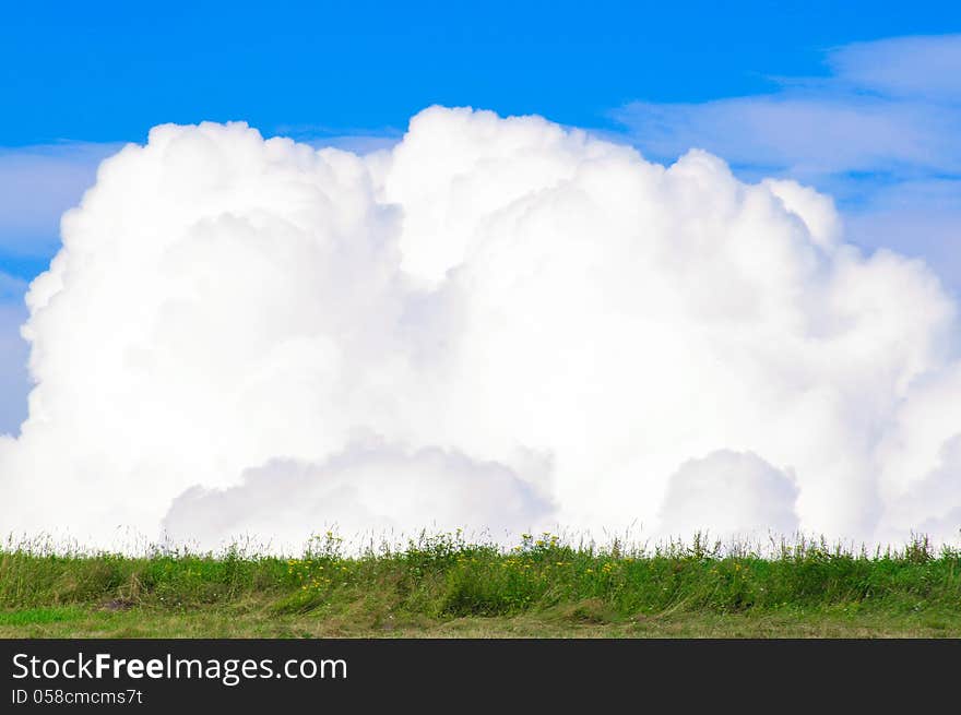 Beautiful clouds in the blue sky on the background of meadows. Beautiful clouds in the blue sky on the background of meadows