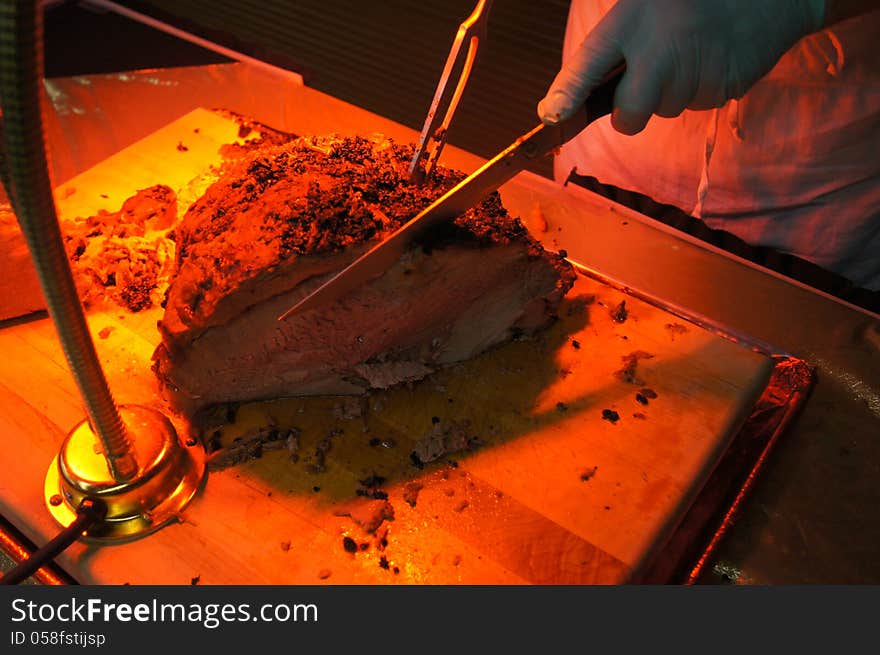 Carving Heated Roast Beef on Cutting Board and under food heat lamp. Carving Heated Roast Beef on Cutting Board and under food heat lamp